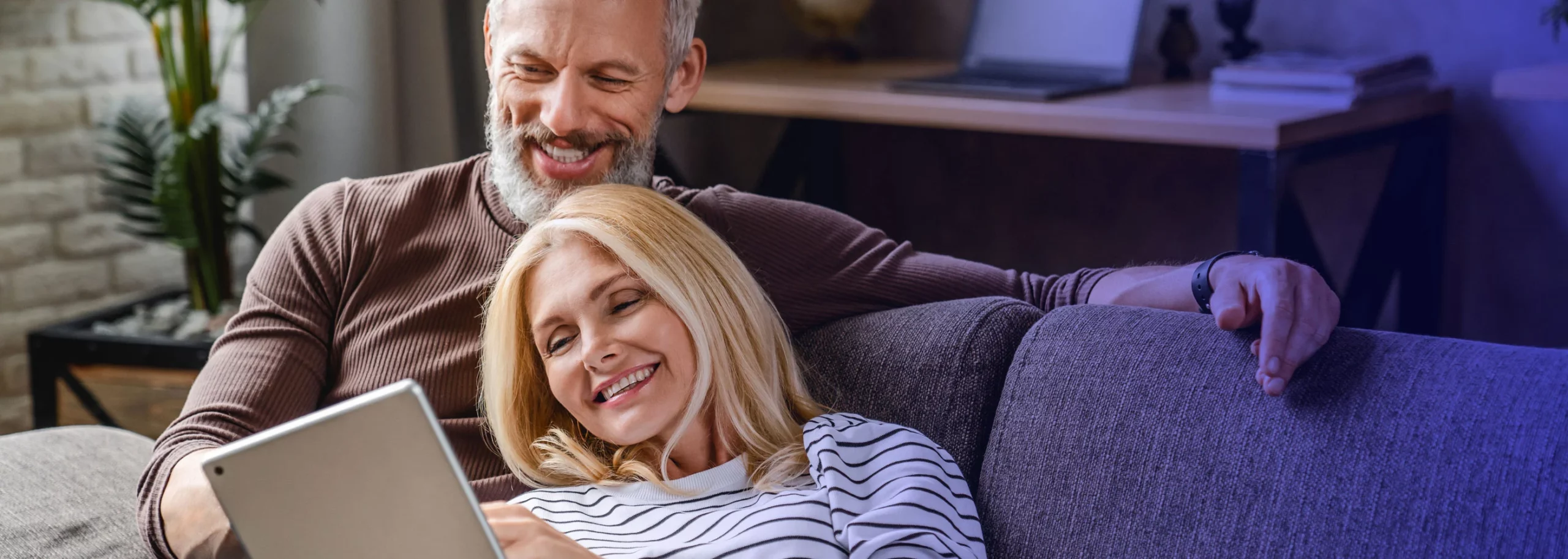 A middle age couple enjoying their time scrolling on the tablet and seraching for holiday destination