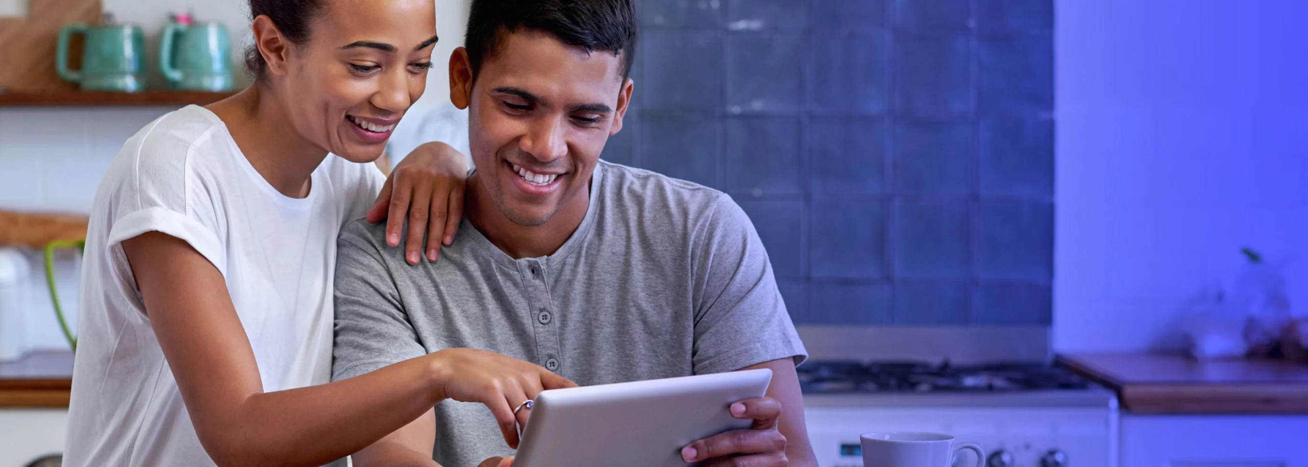 A youthful couple looking at their tablet and making an online purchase