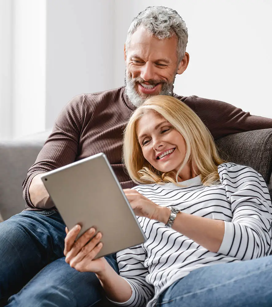 A middle age couple enjoying their time scrolling on the tablet and seraching for holiday destination