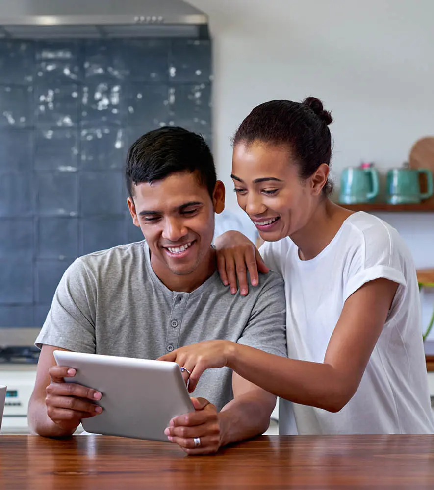 A youthful couple looking at their tablet and making an online purchase