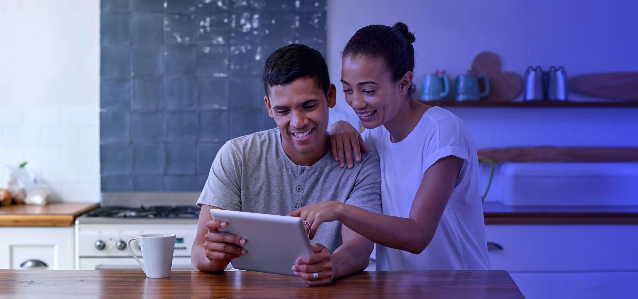 A youthful couple looking at their tablet and making an online purchase