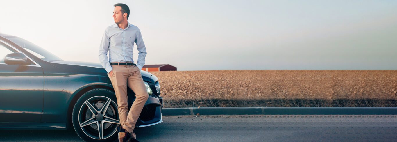 Young man stands with his new automobile