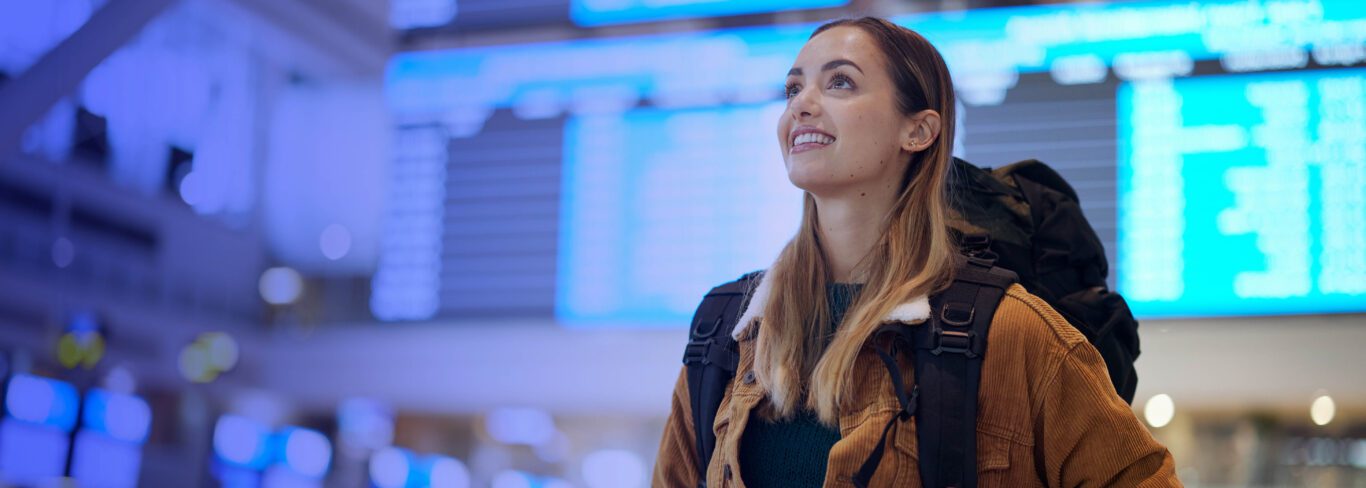 Traveller at the airport looking at her flight schedule no the boarding screen