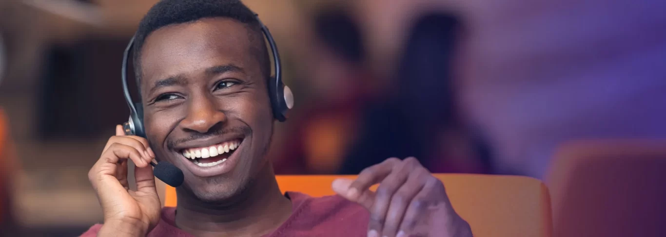 Call center agent in office smiling and speaking with a customer on phone